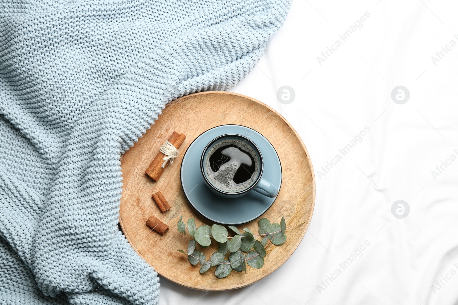 Flat lay composition with hot drink and warm plaid on white bedsheet Photo of Flat lay composition with hot drink and warm plaid on white bedsheet