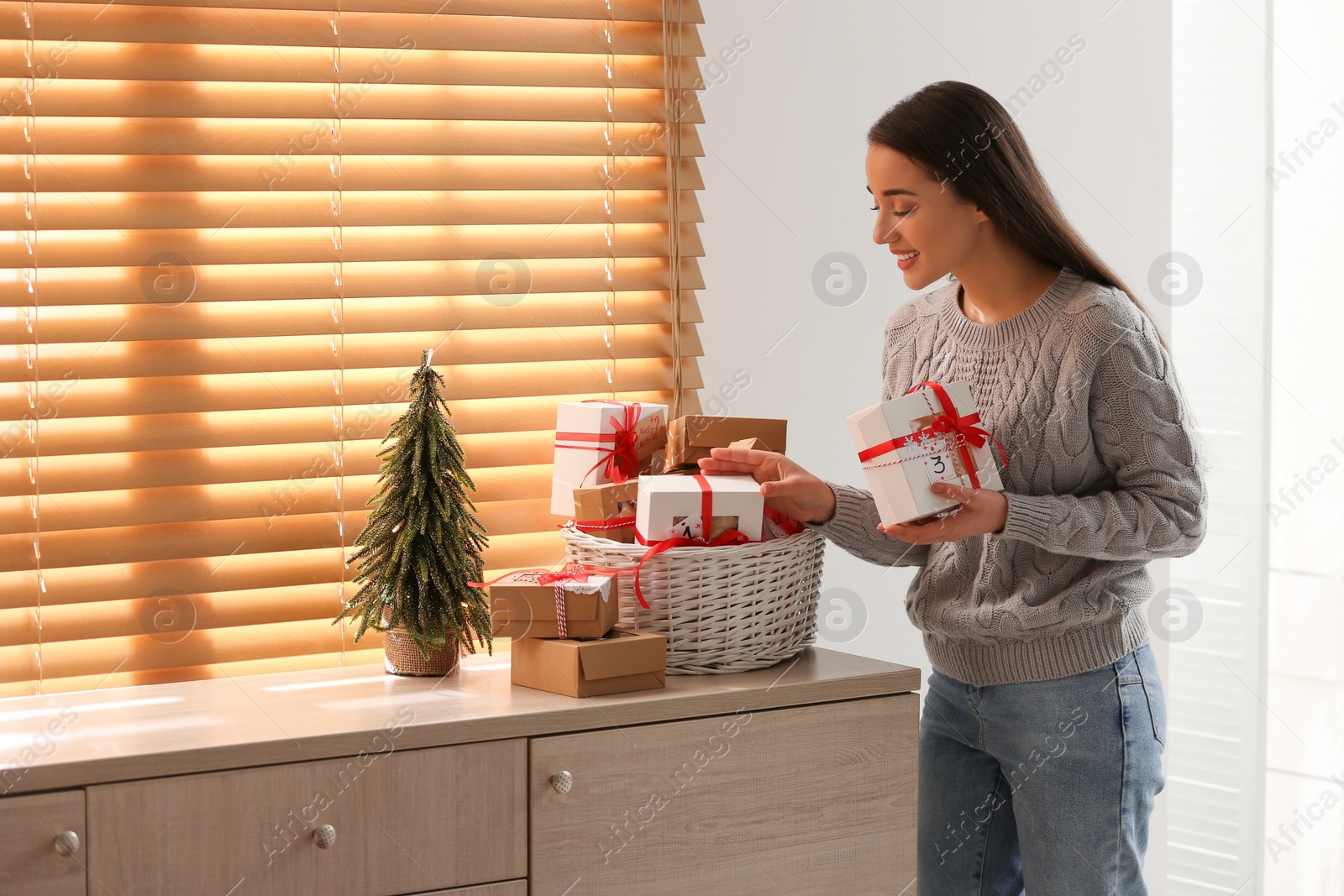 Woman with Christmas gifts at home. Advent calendar in basket Photo of Woman with Christmas gifts at home. Advent calendar in basket