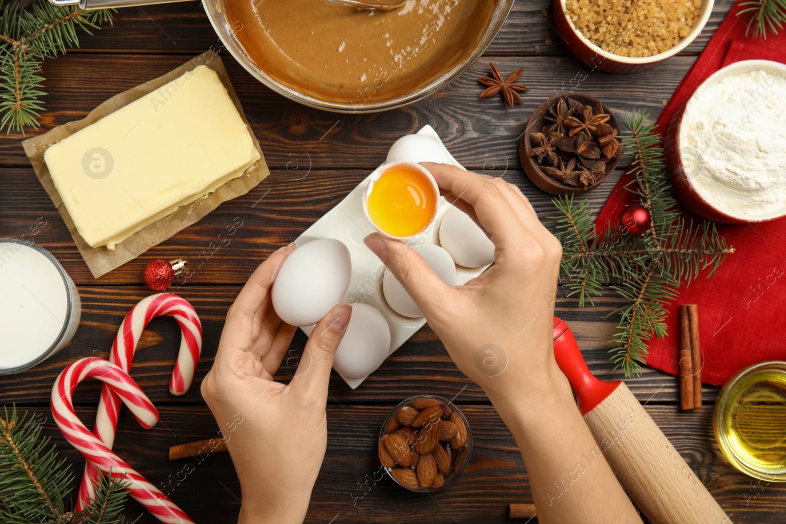 Woman cooking traditional Christmas cake at wooden table with ingredients, top view Photo of Woman cooking traditional Christmas cake at wooden table with ingredients, top view