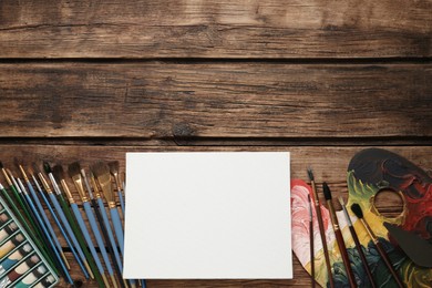 Blank canvas, brushes, palette and paints on wooden table, flat lay. Space for text Photo of Blank canvas, brushes, palette and paints on wooden table, flat lay. Space for text
