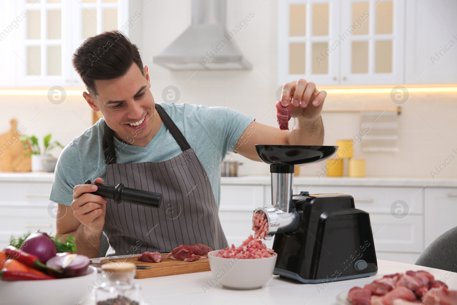 Man using modern meat grinder in kitchen Photo of Man using modern meat grinder in kitchen