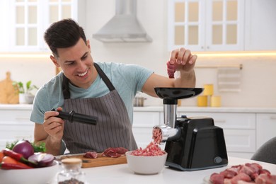 Man using modern meat grinder in kitchen Photo of Man using modern meat grinder in kitchen