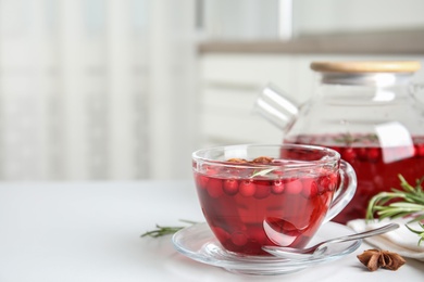 Tasty hot cranberry tea in glass cup on white table. Space for text Photo of Tasty hot cranberry tea in glass cup on white table. Space for text