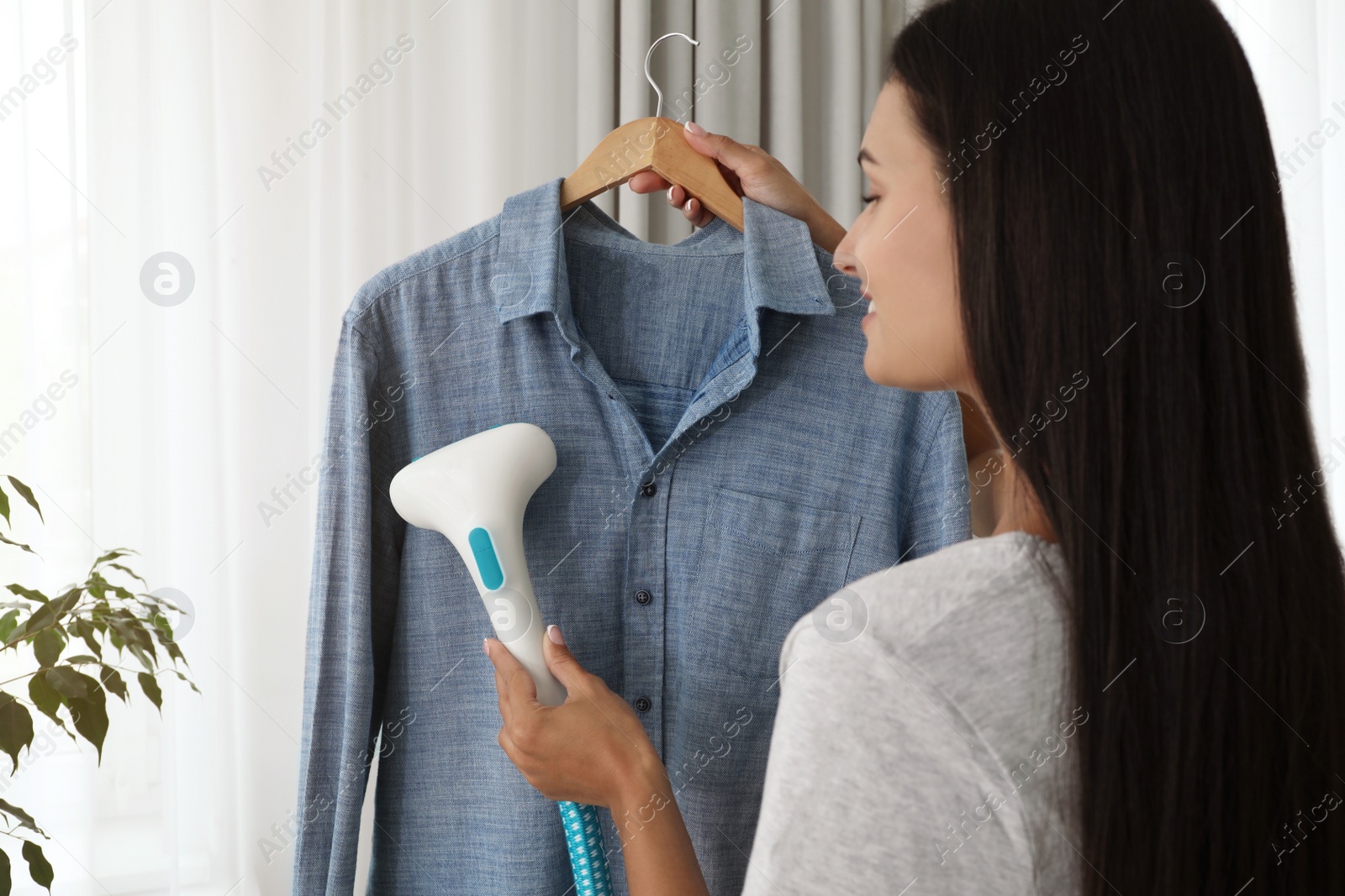 Woman steaming shirt on hanger at home Photo of Woman steaming shirt on hanger at home