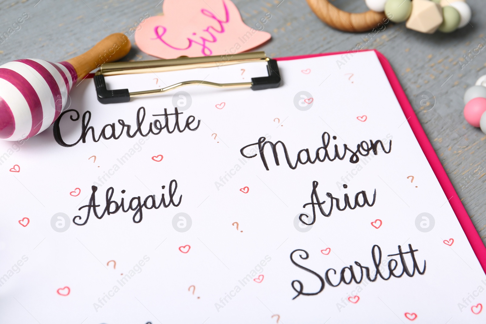 Clipboard with different baby names and toys on grey table, closeup Photo of Clipboard with different baby names and toys on grey table, closeup