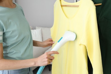 Woman steaming yellow shirt at home, closeup Photo of Woman steaming yellow shirt at home, closeup