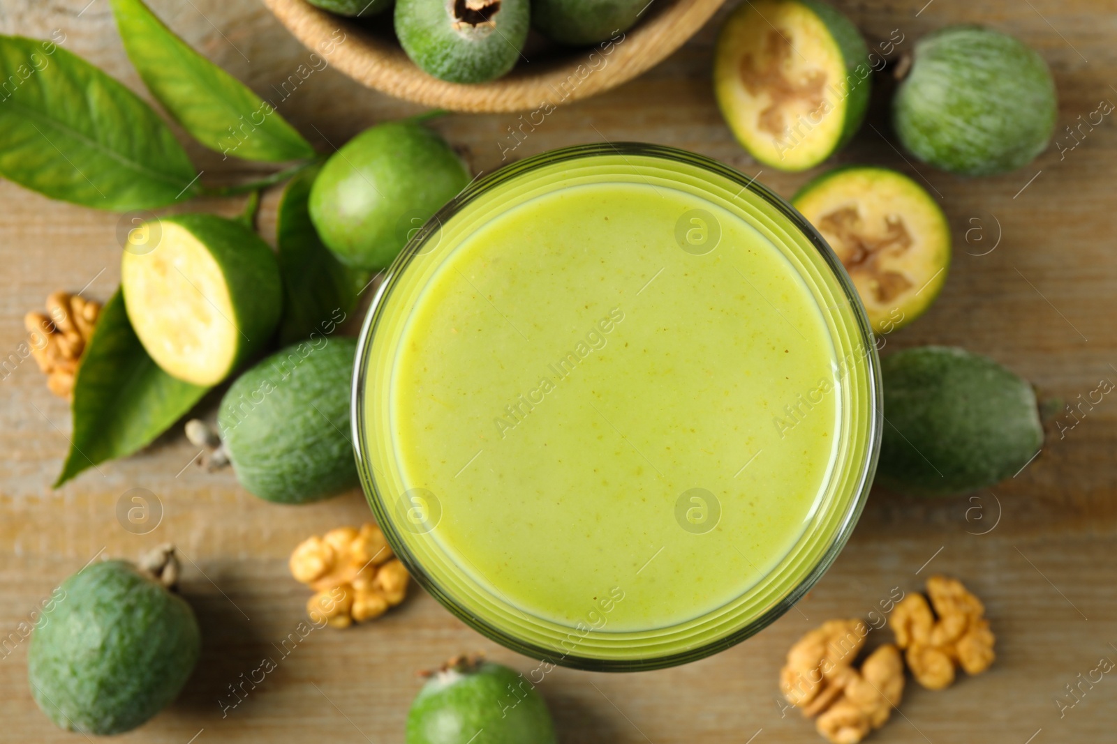 Fresh feijoa smoothie in glass on wooden table, flat lay Photo of Fresh feijoa smoothie in glass on wooden table, flat lay