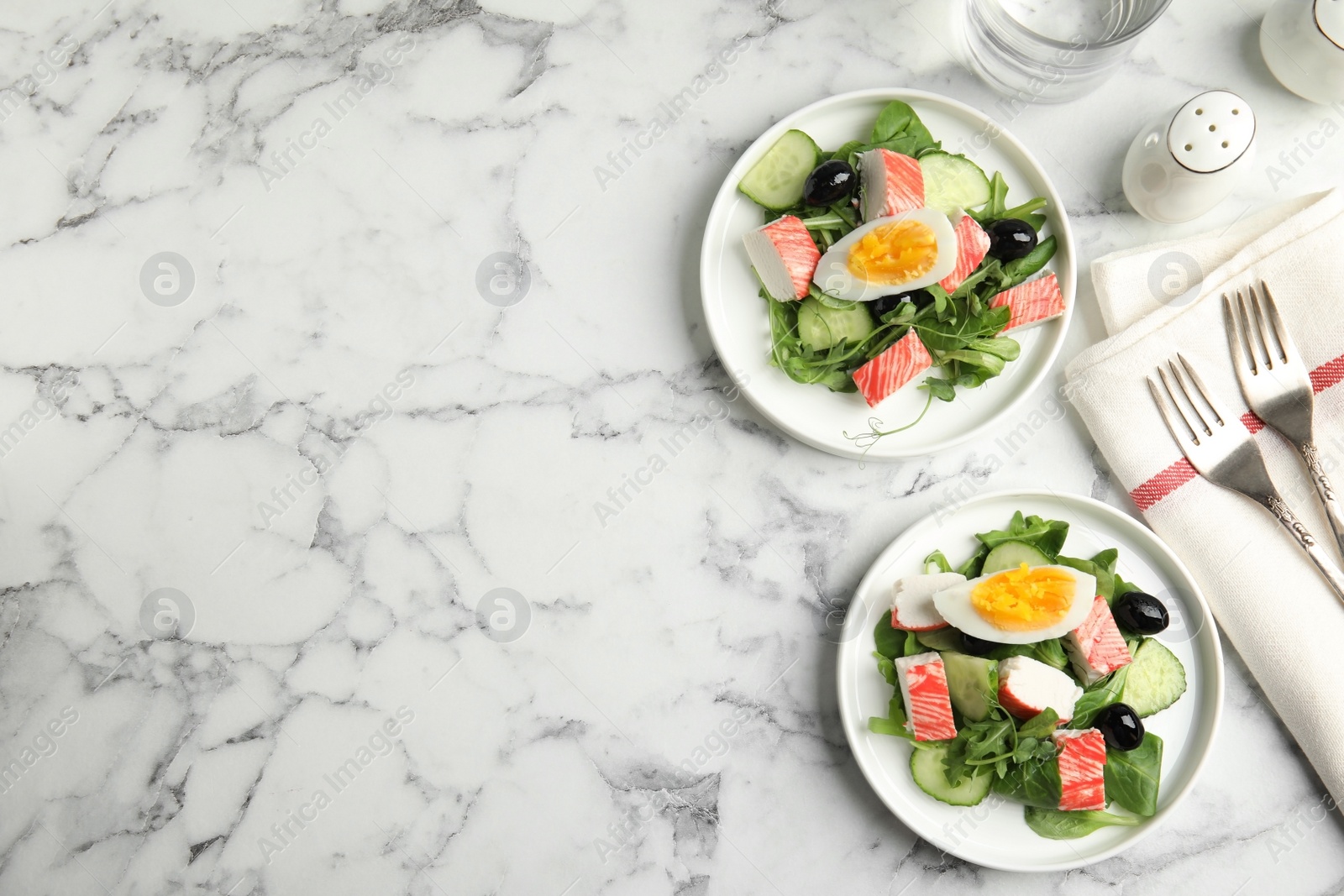 Delicious crab stick salad served on white marble table, flat lay. Space for text Photo of Delicious crab stick salad served on white marble table, flat lay. Space for text