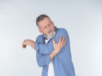 Man suffering from arm pain on light background Photo of Man suffering from arm pain on light background