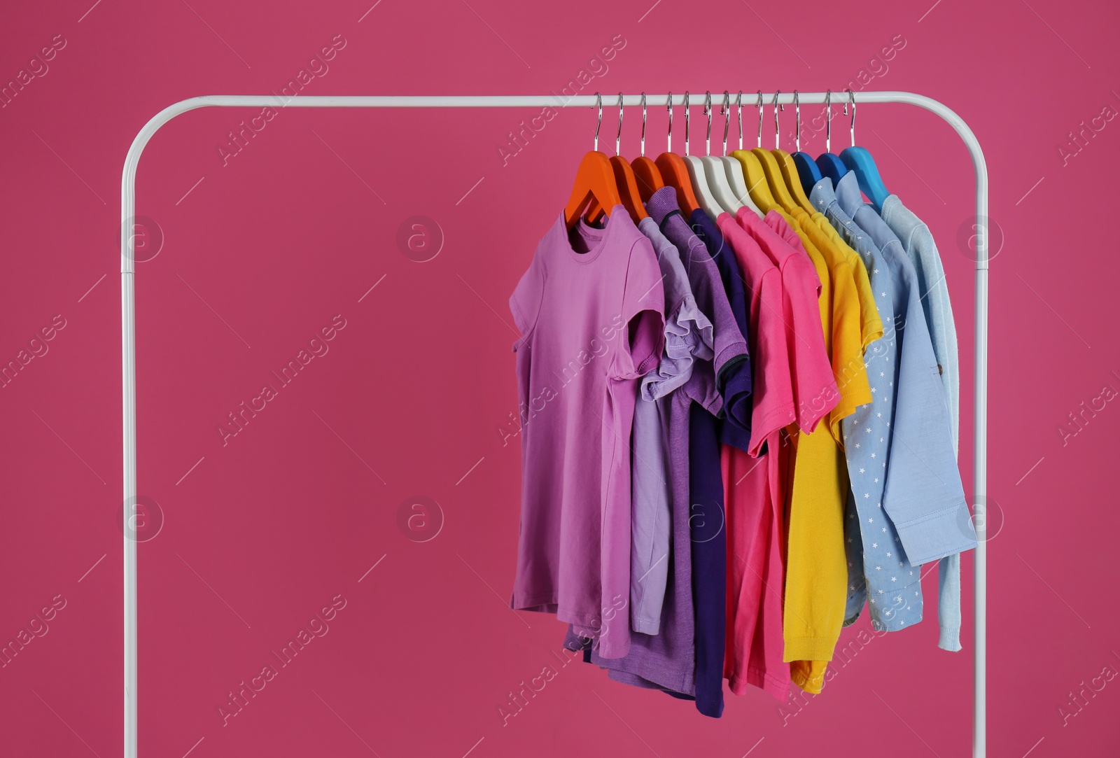 Rack with stylish children clothes on pink background Photo of Rack with stylish children clothes on pink background