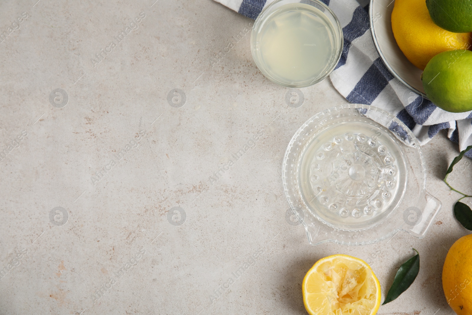 Glass squeezer with juice and lemons on light table, flat lay. Space for text Photo of Glass squeezer with juice and lemons on light table, flat lay. Space for text