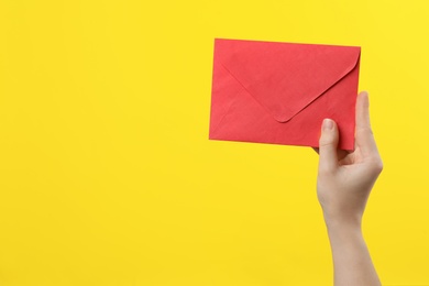 Woman holding red paper envelope on yellow background, closeup. Space for text Photo of Woman holding red paper envelope on yellow background, closeup. Space for text
