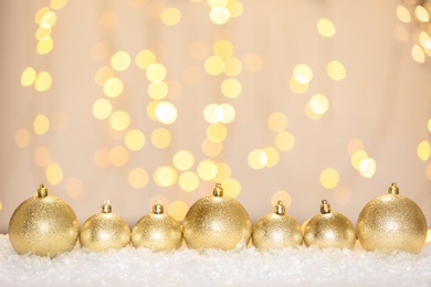 Beautiful shiny Christmas balls on snow against blurred festive lights, space for text Photo of Beautiful shiny Christmas balls on snow against blurred festive lights, space for text