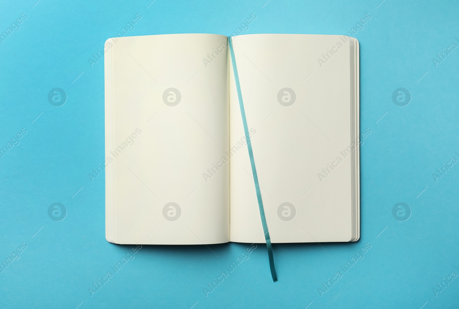 Stylish open notebook with blank sheets on light blue background, top view Photo of Stylish open notebook with blank sheets on light blue background, top view
