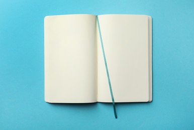 Stylish open notebook with blank sheets on light blue background, top view Photo of Stylish open notebook with blank sheets on light blue background, top view