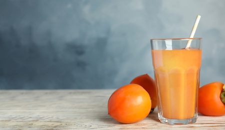 Tasty persimmon smoothie and fresh fruits on white wooden table against light blue background. Space for text Photo of Tasty persimmon smoothie and fresh fruits on white wooden table against light blue background. Space for text