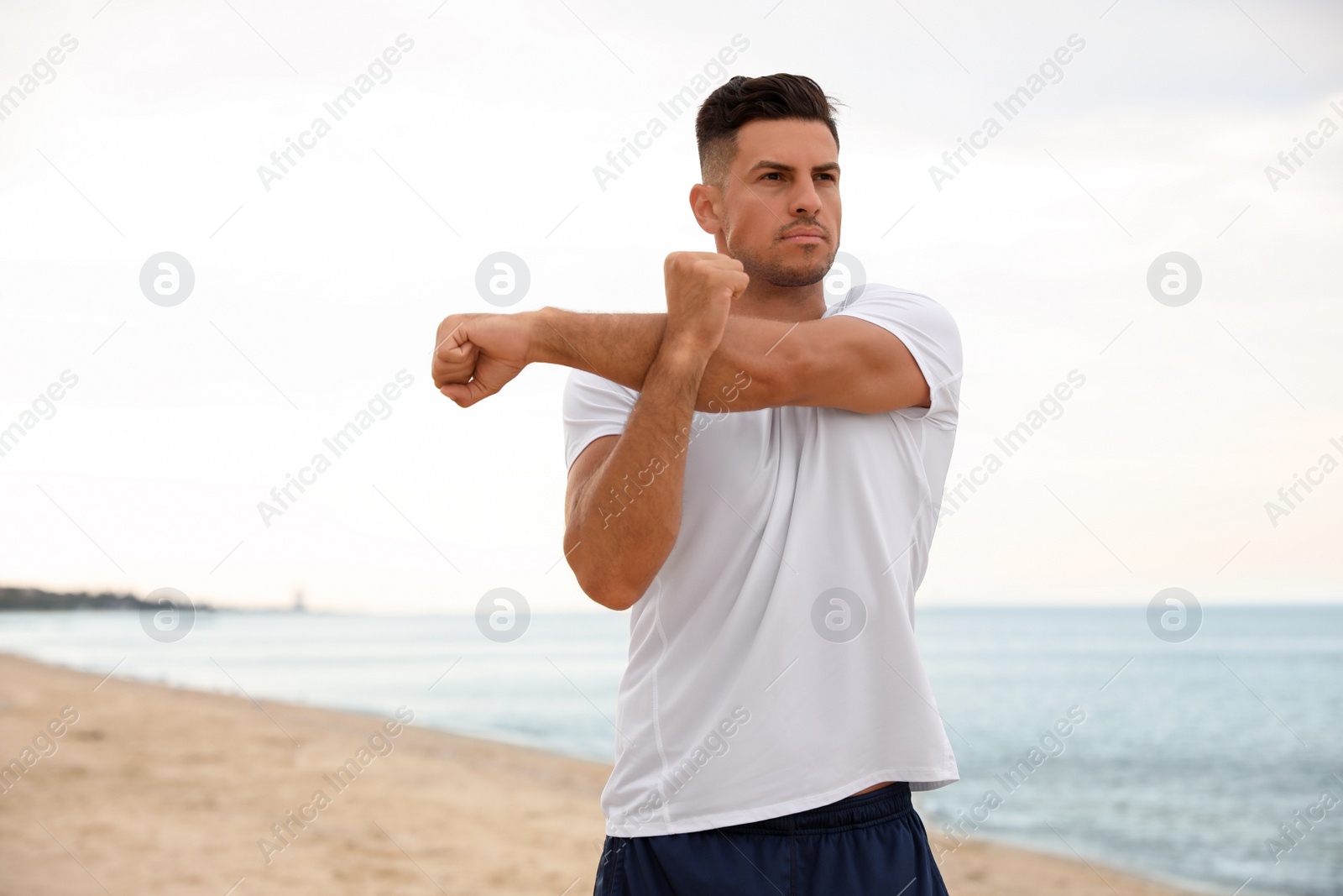 Muscular man doing exercise on beach. Body training Photo of Muscular man doing exercise on beach. Body training