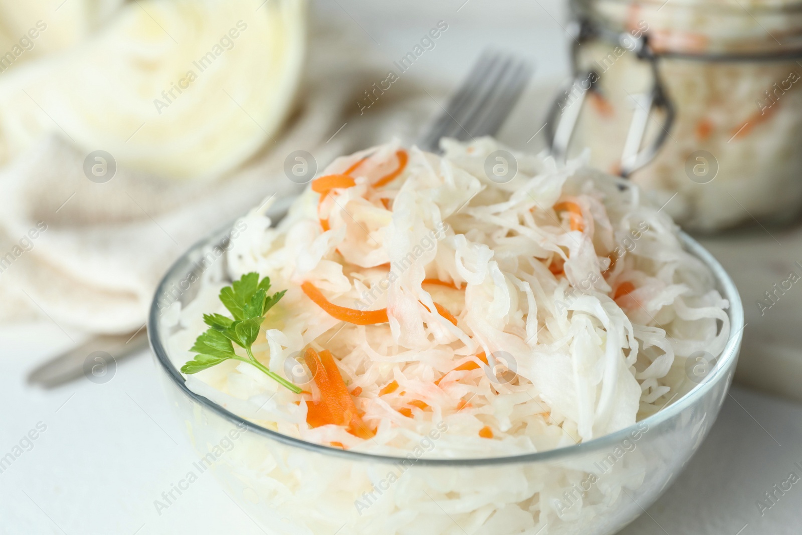 Glass bowl of tasty fermented cabbage on white table, closeup Photo of Glass bowl of tasty fermented cabbage on white table, closeup