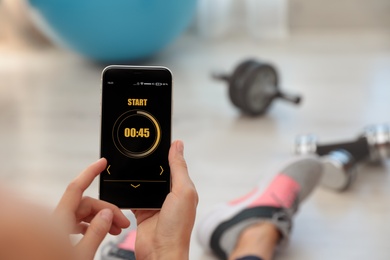 Photo of Young woman using fitness app on smartphone indoors, closeup. Space for text