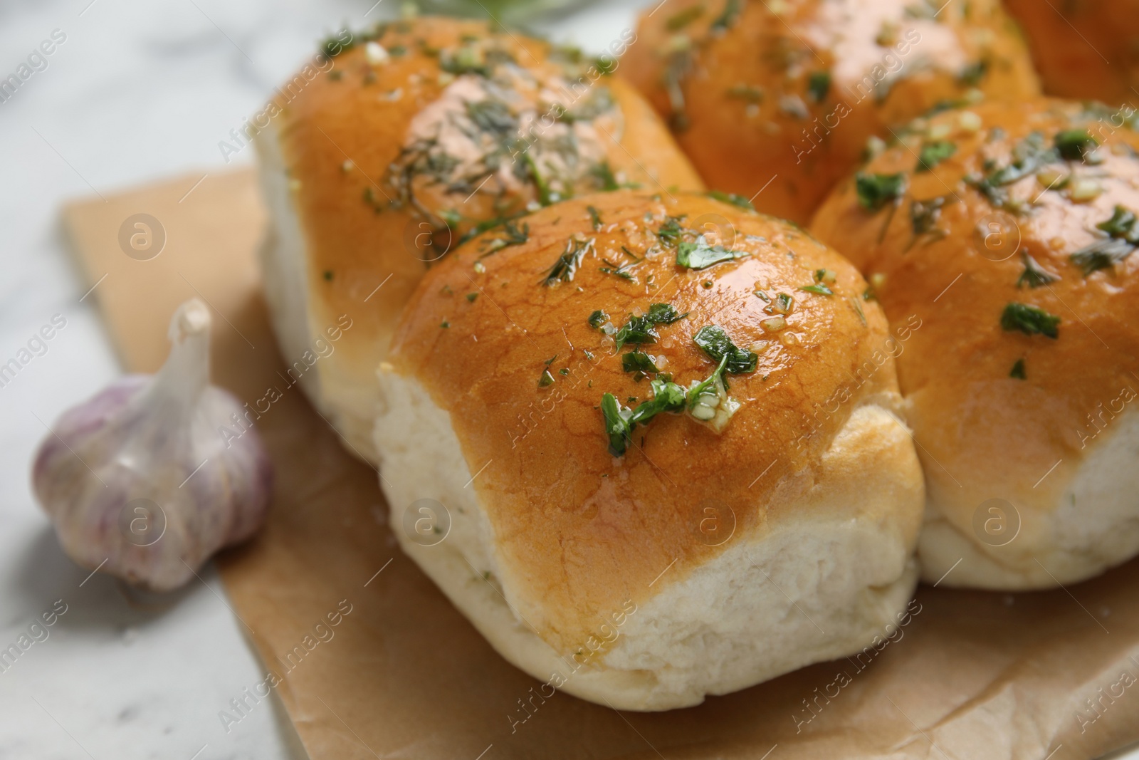 Traditional pampushka buns with garlic and herbs on white table, closeup Photo of Traditional pampushka buns with garlic and herbs on white table, closeup