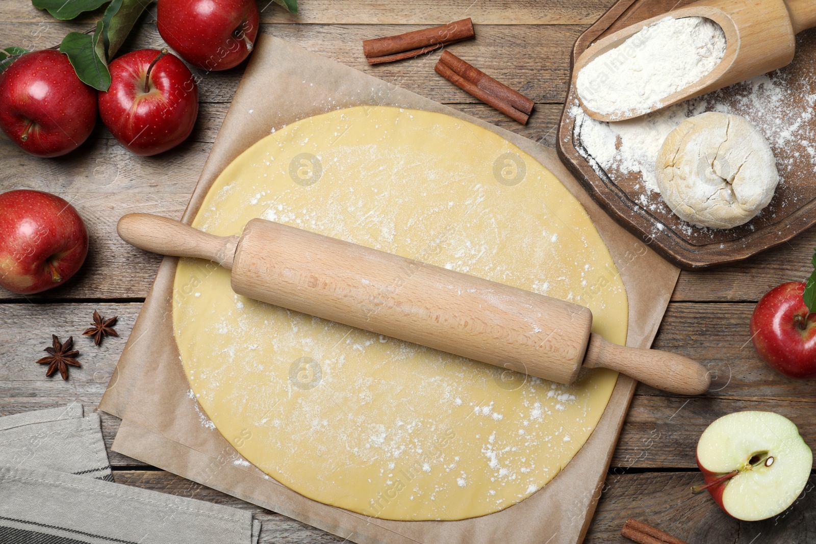 Dough for apple pie and ingredients on wooden table, flat lay Photo of Dough for apple pie and ingredients on wooden table, flat lay