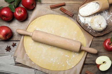 Dough for apple pie and ingredients on wooden table, flat lay Photo of Dough for apple pie and ingredients on wooden table, flat lay