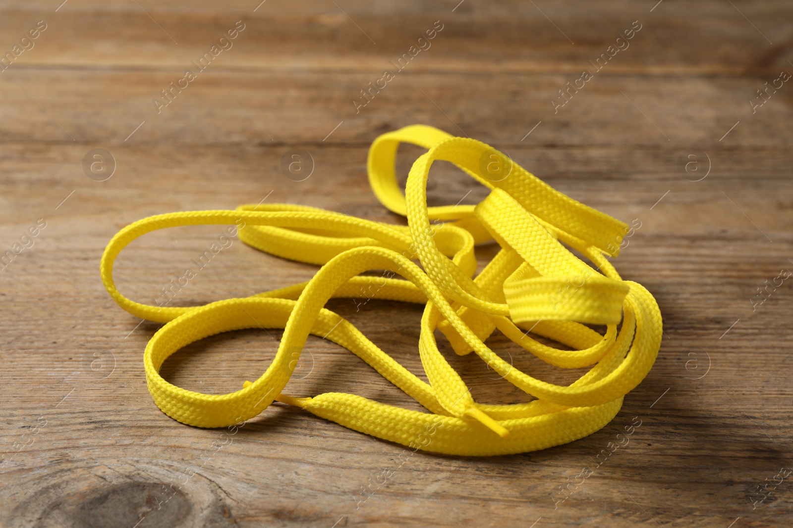 Yellow shoelace on wooden background. Stylish accessory Photo of Yellow shoelace on wooden background. Stylish accessory