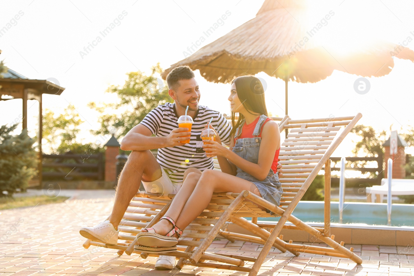 Happy couple with cups of refreshing drink resting in deck chairs outdoors Image of Happy couple with cups of refreshing drink resting in deck chairs outdoors