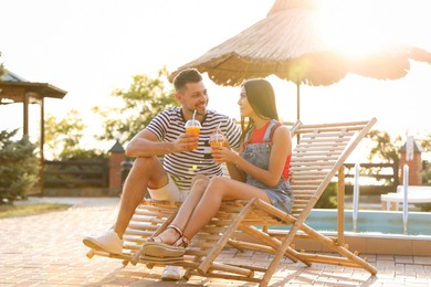 Happy couple with cups of refreshing drink resting in deck chairs outdoors Image of Happy couple with cups of refreshing drink resting in deck chairs outdoors