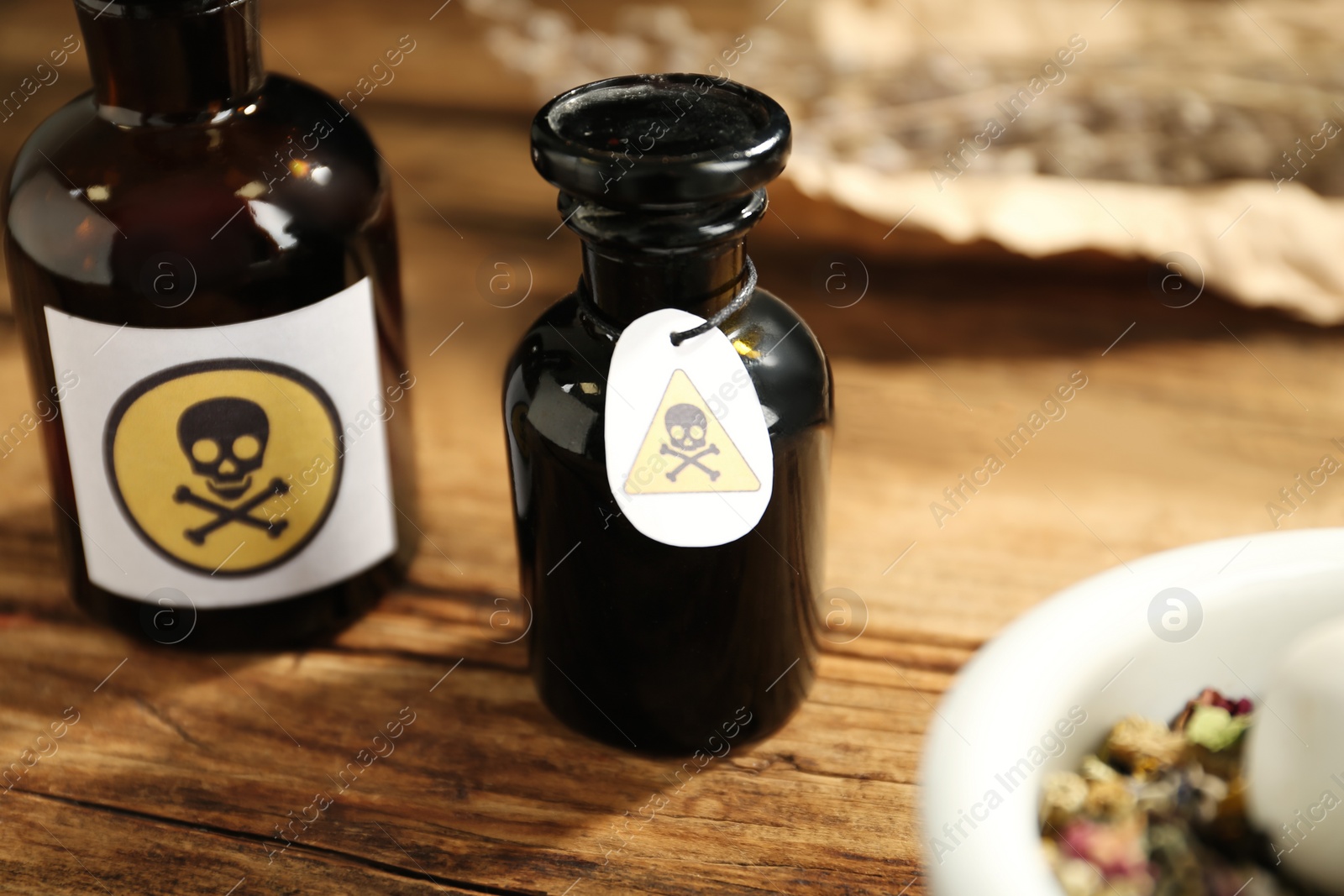 Open glass bottle of poison with warning sign on wooden table, closeup Photo of Open glass bottle of poison with warning sign on wooden table, closeup