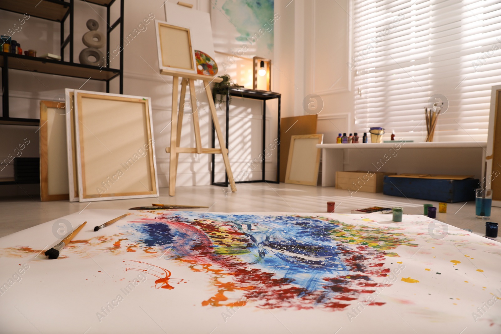 Wooden easel and abstract picture in art studio Photo of Wooden easel and abstract picture in art studio