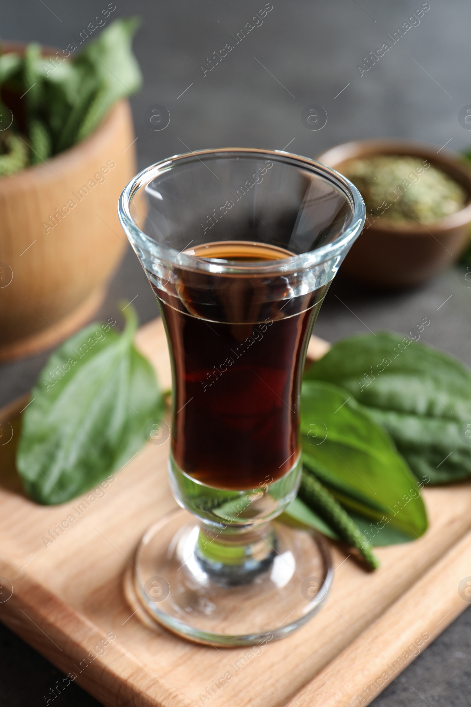 Glass of broadleaf plantain oil on wooden board Photo of Glass of broadleaf plantain oil on wooden board