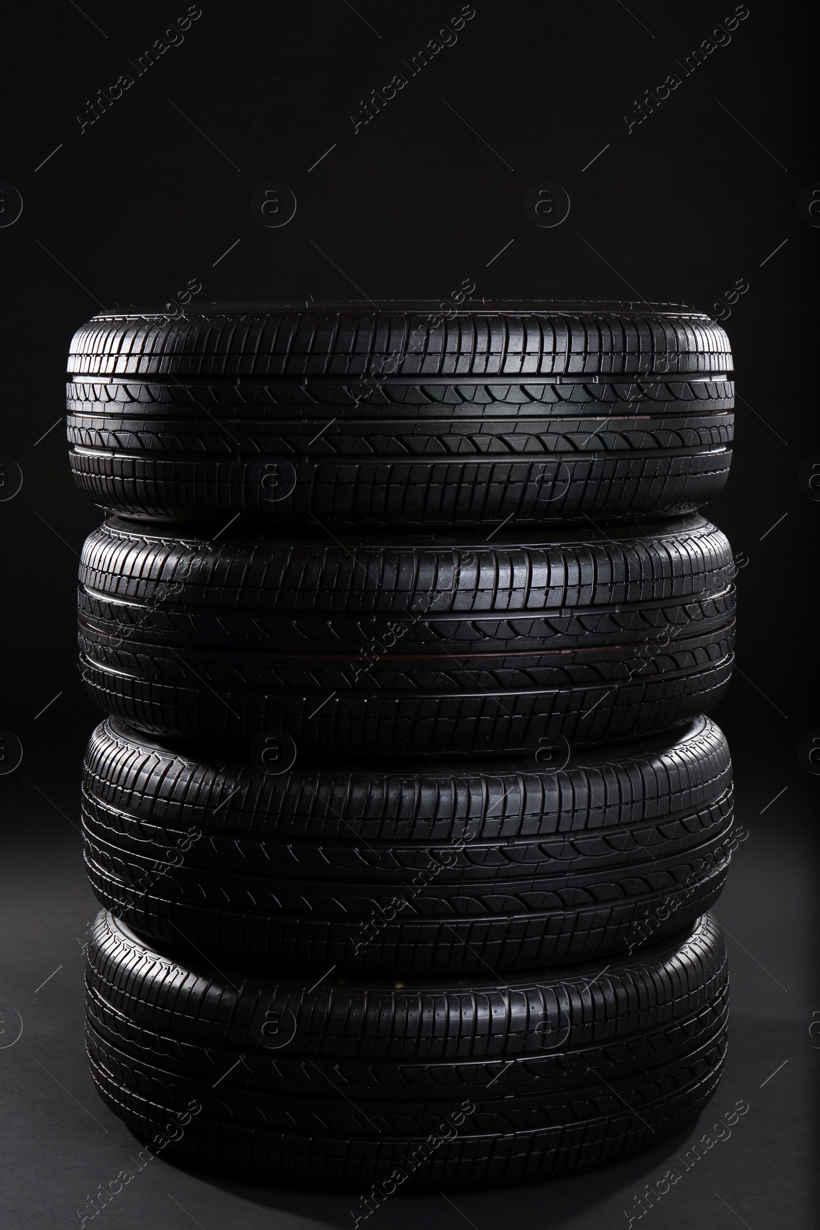 Stack of car tires on black background Photo of Stack of car tires on black background