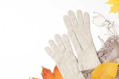 Stylish woolen gloves, scarf, glasses and dry leaves on white background, top view Photo of Stylish woolen gloves, scarf, glasses and dry leaves on white background, top view