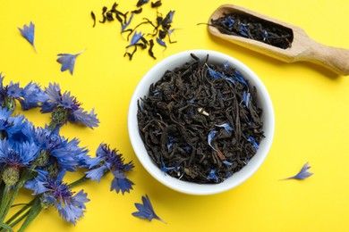 Flat lay composition with dry tea leaves and cornflowers on yellow background Photo of Flat lay composition with dry tea leaves and cornflowers on yellow background