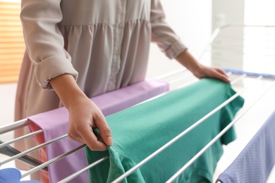 Young woman hanging clean laundry on drying rack at home, closeup Photo of Young woman hanging clean laundry on drying rack at home, closeup