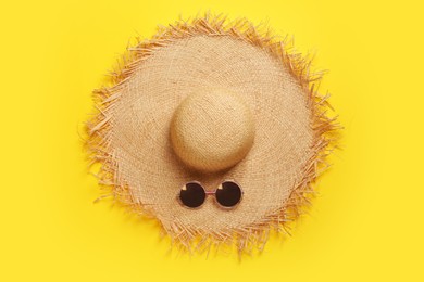 Straw hat and sunglasses on yellow background, flat lay. Stylish headdress Photo of Straw hat and sunglasses on yellow background, flat lay. Stylish headdress