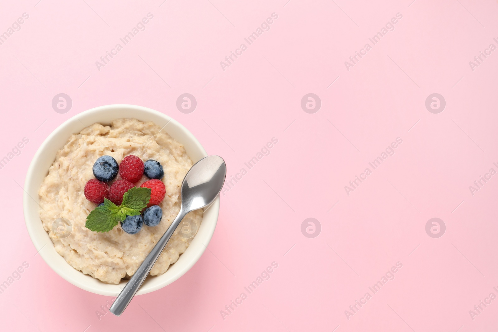 Tasty oatmeal porridge with raspberries, blueberries and spoon in bowl on pink background, top view Photo of Tasty oatmeal porridge with raspberries, blueberries and spoon in bowl on pink background, top view