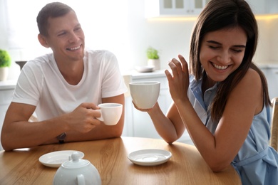 Man and woman talking while drinking tea at table in kitchen Photo of Man and woman talking while drinking tea at table in kitchen