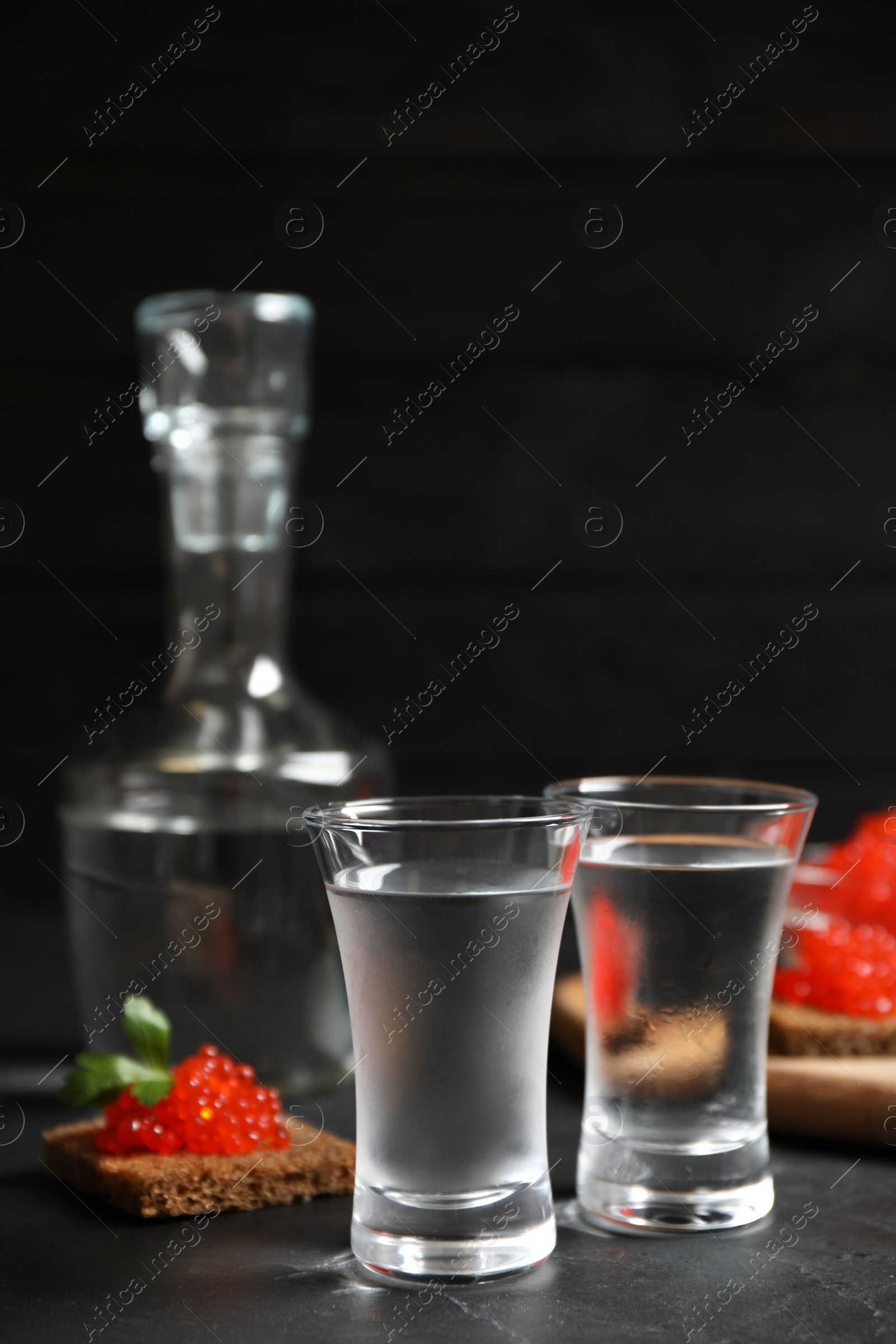 Cold Russian vodka and sandwiches with red caviar on black table, closeup Photo of Cold Russian vodka and sandwiches with red caviar on black table, closeup