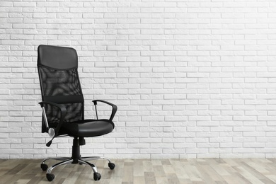 Comfortable office chair near white brick wall indoors. Space for text Photo of Comfortable office chair near white brick wall indoors. Space for text