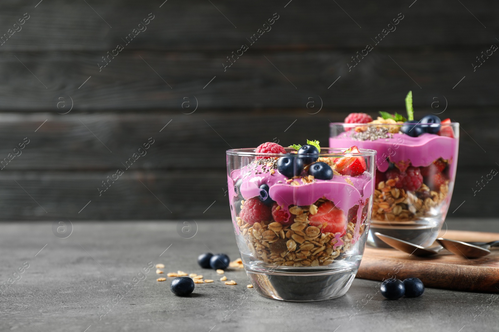Tasty dessert with acai smoothie, granola and berries on grey table. Space for text Image of Tasty dessert with acai smoothie, granola and berries on grey table. Space for text