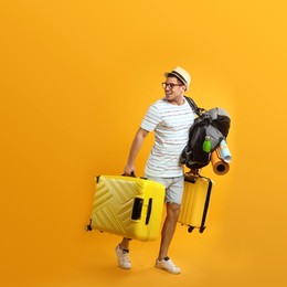 Male tourist with travel backpack and suitcases on yellow background Photo of Male tourist with travel backpack and suitcases on yellow background