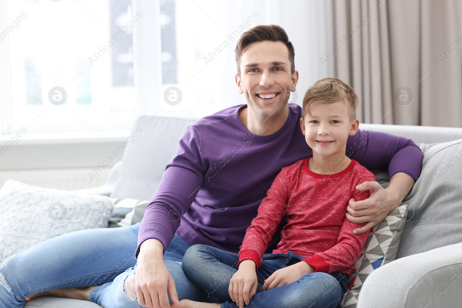 Dad and his son sitting on sofa at home Photo of Dad and his son sitting on sofa at home