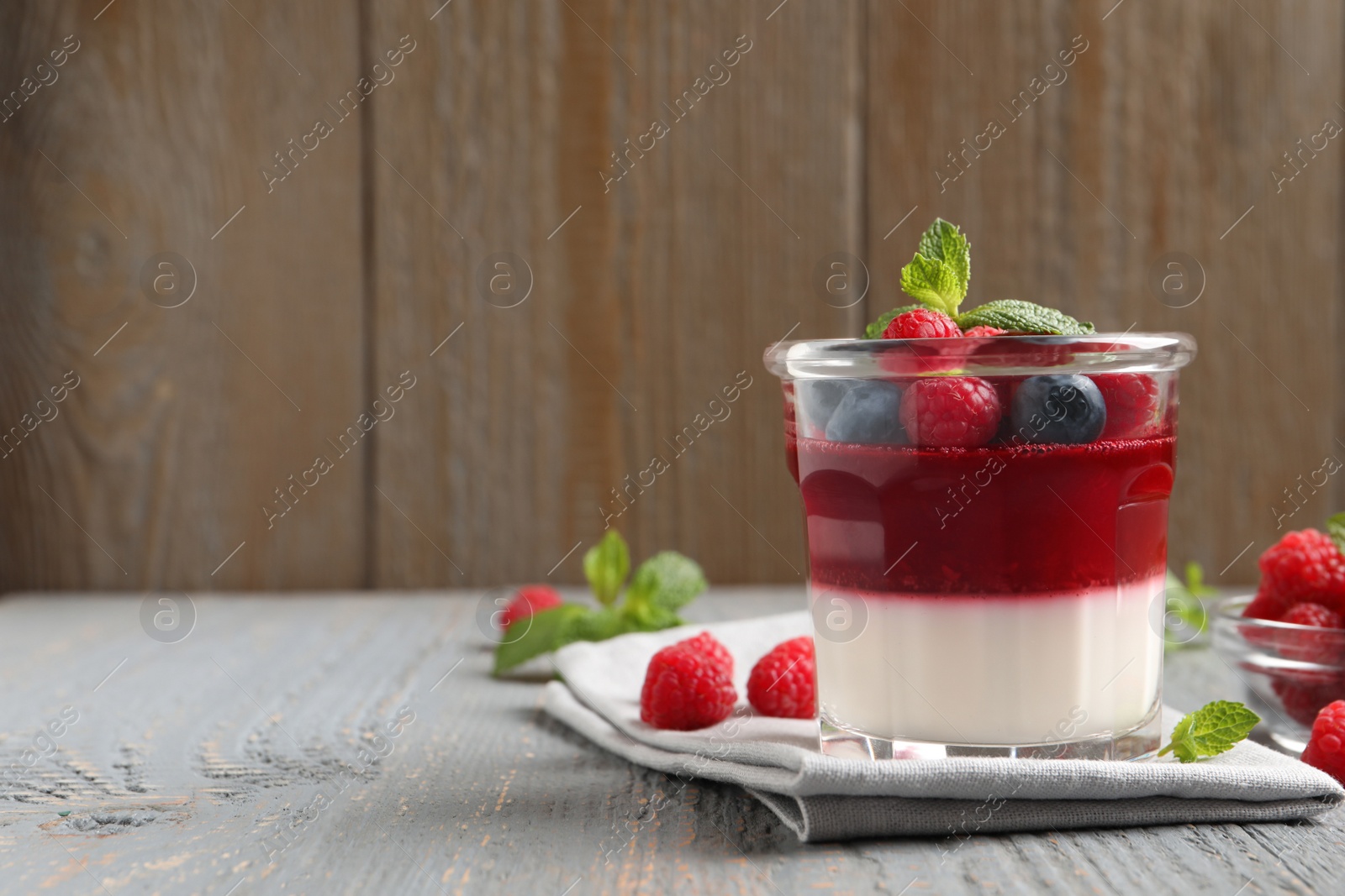 Delicious panna cotta with berries on grey wooden table. Space for text Photo of Delicious panna cotta with berries on grey wooden table. Space for text