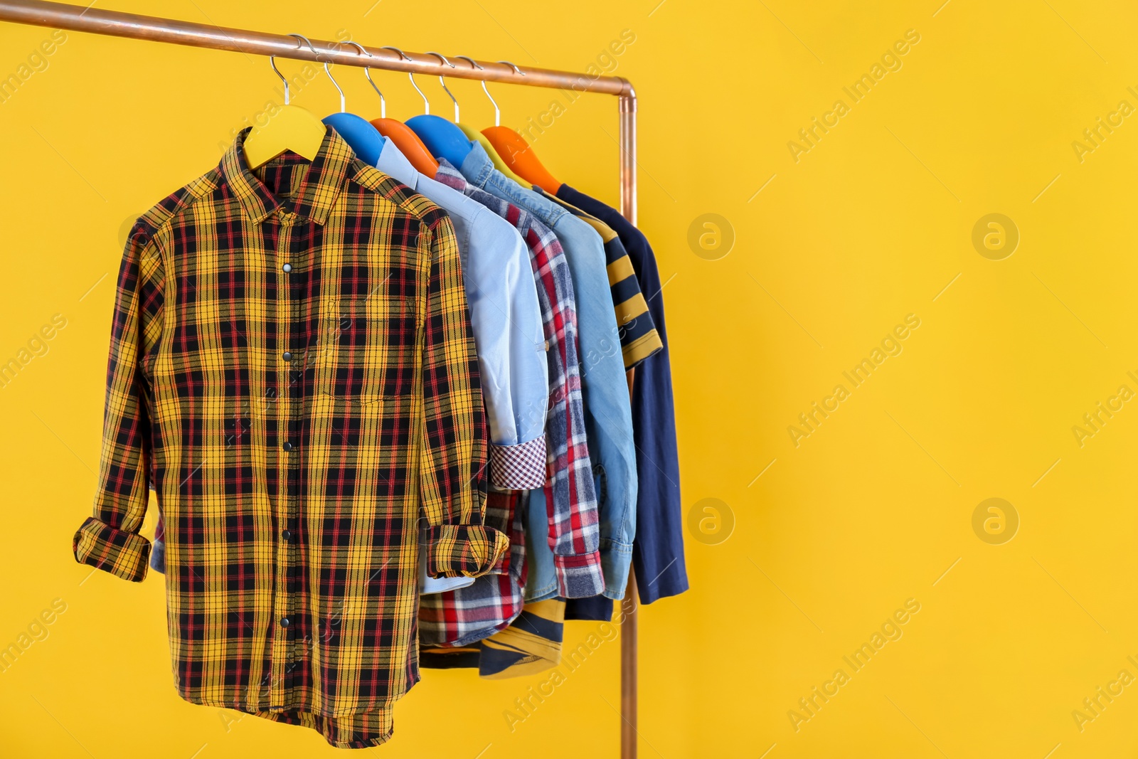 Rack with stylish children clothes on yellow background Photo of Rack with stylish children clothes on yellow background