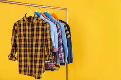 Rack with stylish children clothes on yellow background Photo of Rack with stylish children clothes on yellow background