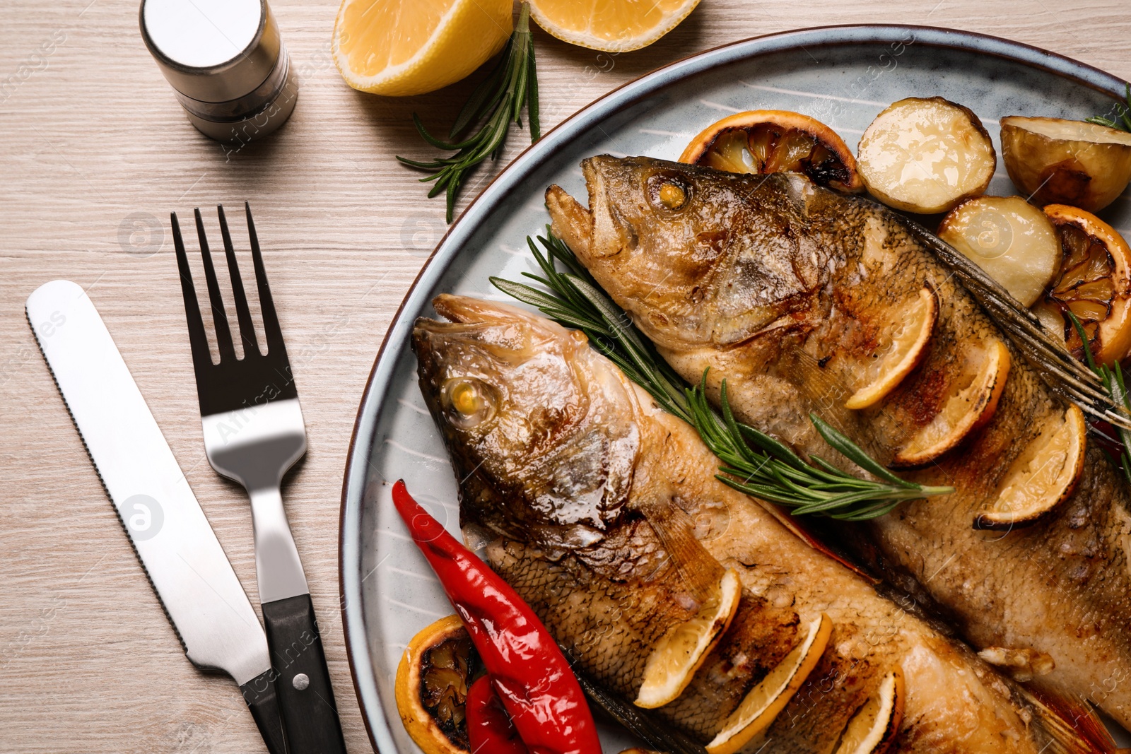 Tasty homemade roasted perches served on wooden table, flat lay. River fish Photo of Tasty homemade roasted perches served on wooden table, flat lay. River fish