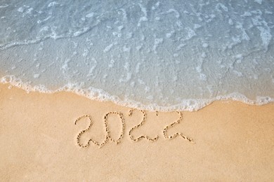 Sandy beach with written 2022 washed by sea. Happy New Year, above view Photo of Sandy beach with written 2022 washed by sea. Happy New Year, above view