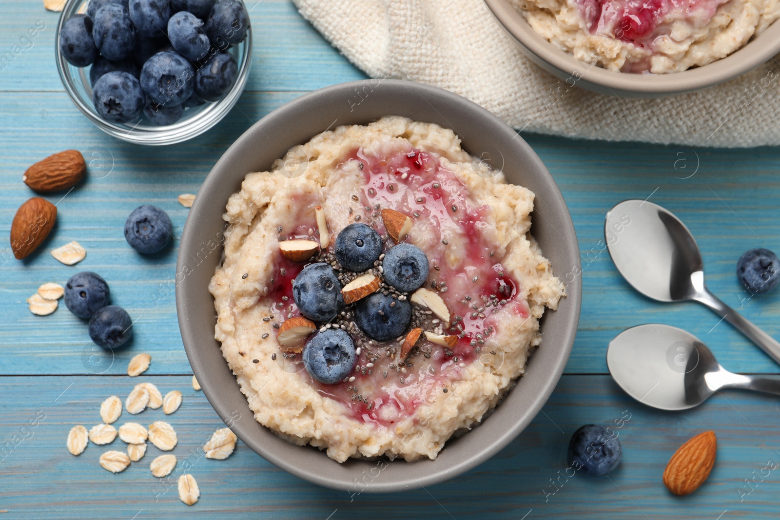 Tasty oatmeal porridge with toppings served on light blue wooden table, flat lay Photo of Tasty oatmeal porridge with toppings served on light blue wooden table, flat lay